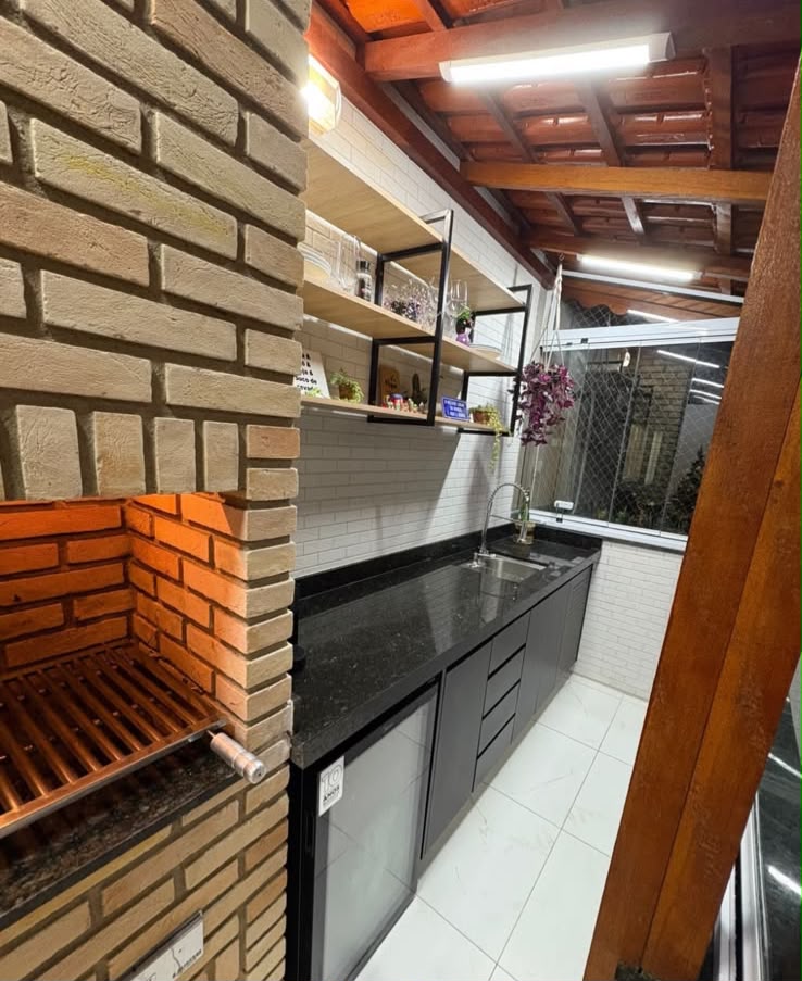 Espaço gourmet com bancada em granito preto, cuba e armários sob medida