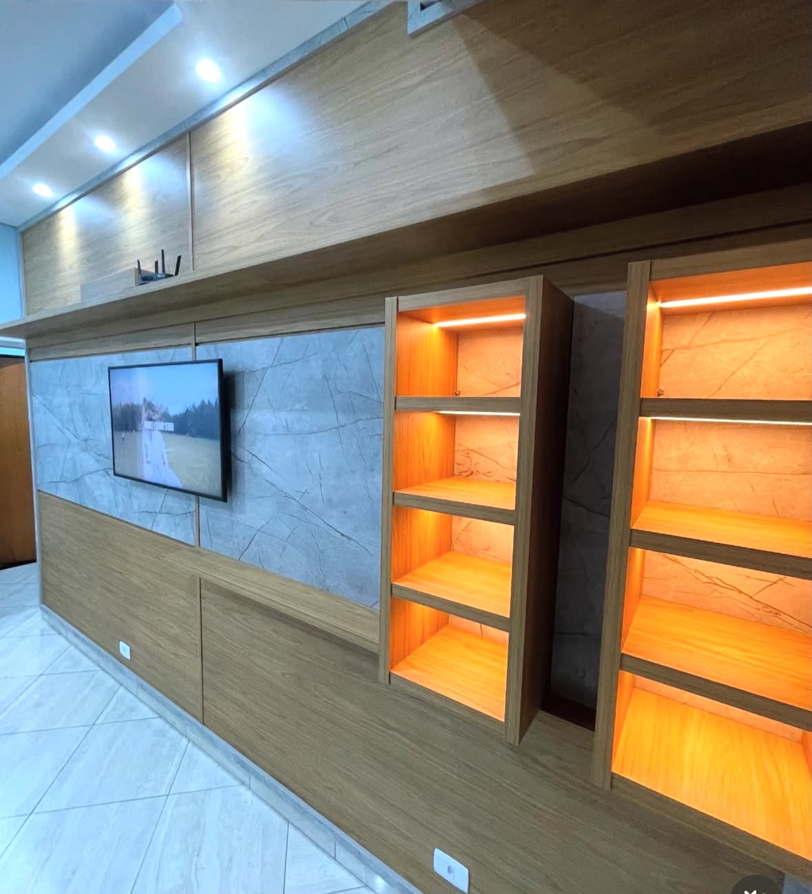 Painel de sala amadeirado com revestimento marmorizado e nichos iluminados