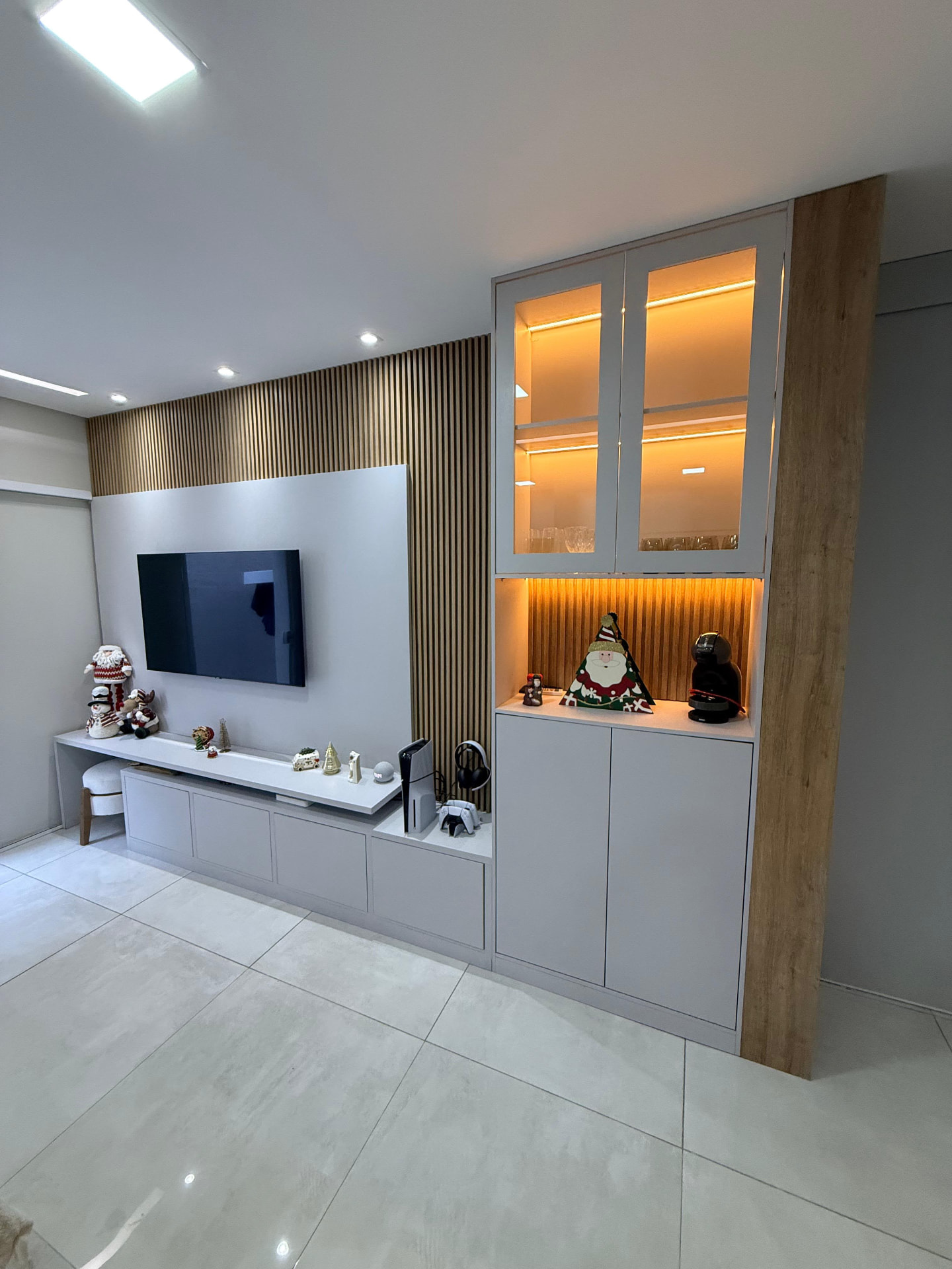 Sala planejada com painel ripado, rack suspenso e cristaleira iluminada